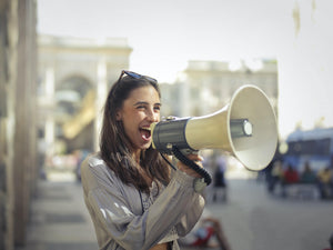 cheerful young woman shouting into megaphone