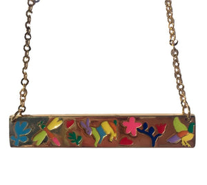 Close-up of a golden artisanal necklace with colorful floral design