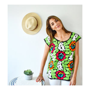 model wearing a colorful mexican blouse with hand embroidered parrot and flower print