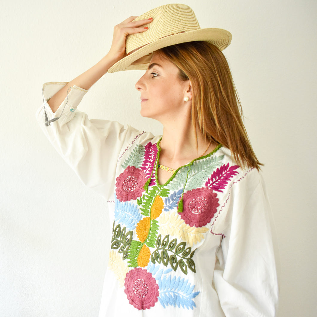 model wearing a white blouse with embroidered flowers