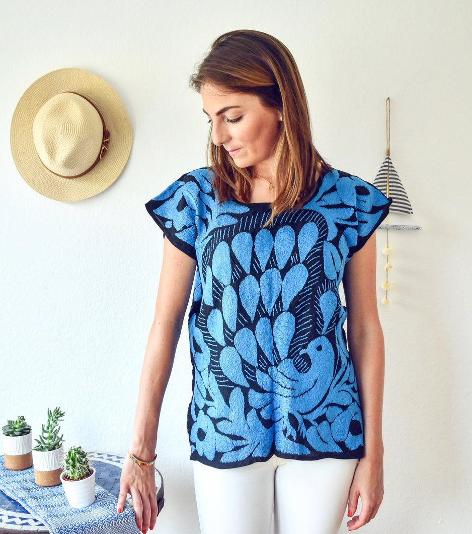 model wearing hand embroidered Mexican blouse with bright blue peacock