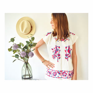 model wearing a white Mexican blouse with peacocks and flowers